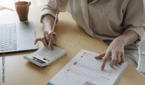 Business woman working in finance and accounting Analyze financial budget with calculator and laptop computer in the office