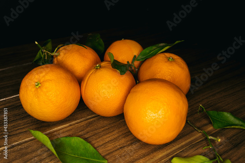 oranges on a wooden board on a black background. side view