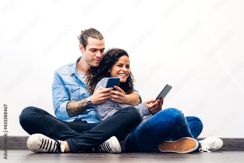 Two friend relax use technology together of smartphone and tablet computer work and checking social apps on wall background.Communication concept Two friend relax use technology together of smartphone and tablet computer work and checking social apps on wall background.Communication concept