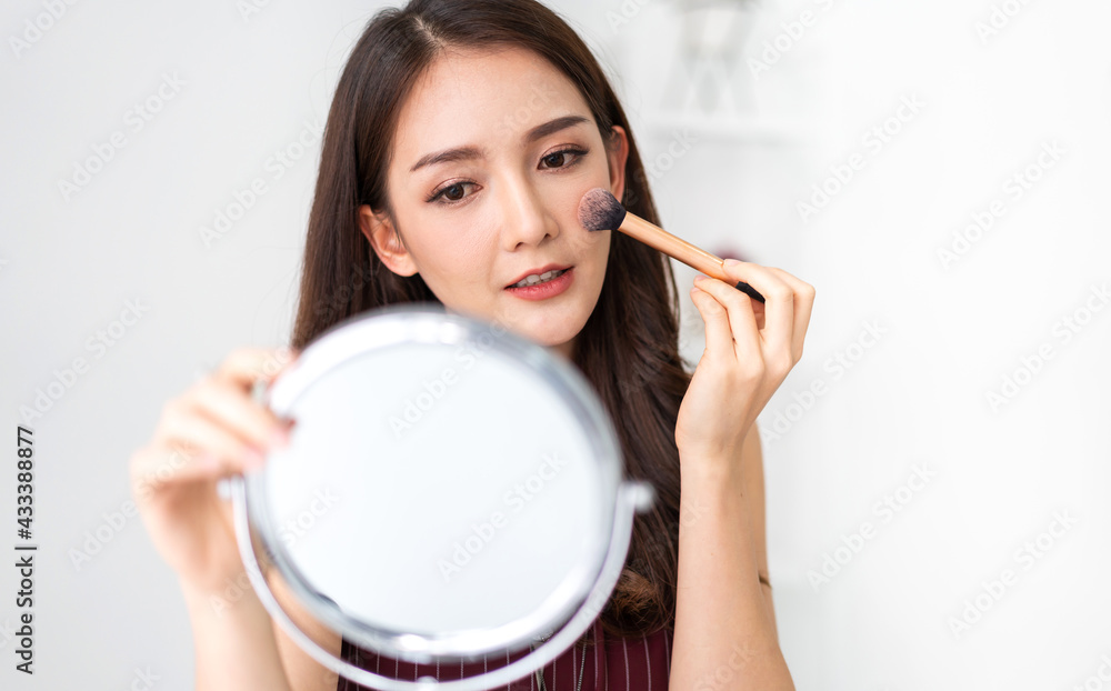 Smiling of young beautiful pretty asian woman clean fresh healthy white skin looking at camara.asian girl holding make-up brushes and make up on face with cosmetics set at home.facial beauty Smiling of young beautiful pretty asian woman clean fresh healthy white skin looking at camara.asian girl holding make-up brushes and make up on face with cosmetics set at home.facial beauty