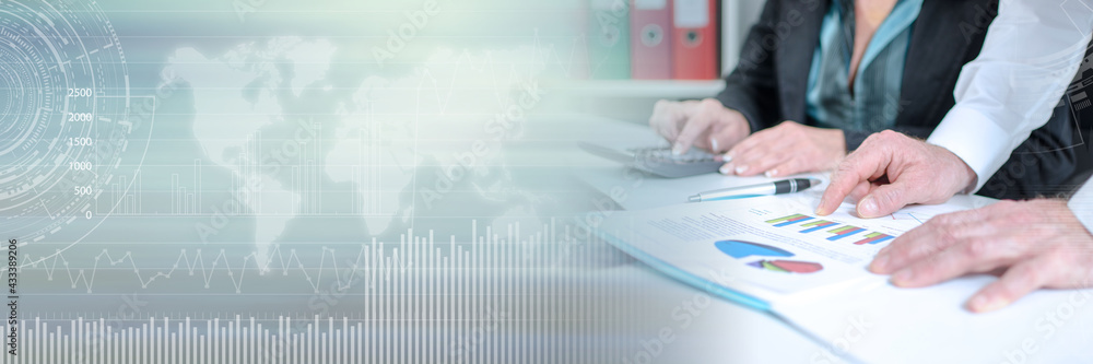 Workteam analyzing graphs and using a calculator; panoramic banner Workteam analyzing graphs and using a calculator; panoramic banner