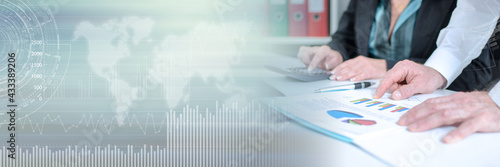 Workteam analyzing graphs and using a calculator; panoramic banner