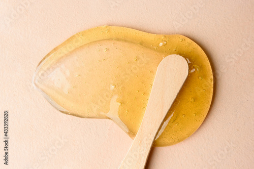 Liquid sugar wax smear with spatula on beige background photo