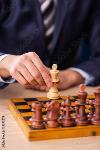 Young male employee playing chess at workplace