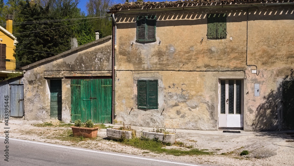 An abandoned cottage in the Italian countryside with green doors and windows (Marche, Italy, Europe)