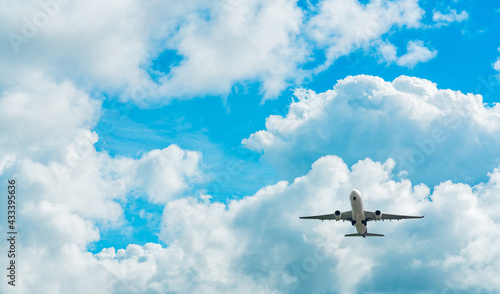Commercial airline flying on blue sky and white fluffy clouds. Under view of airplane flying. Passenger plane after take off or going to landing flight. Vacation travel abroad. Air transportation.