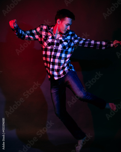 A young man in a studio on a dark background with a multicolored light