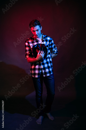 A guy in a plaid shirt with red and blue lighting in the studio on a black background