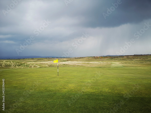 Golf course in the rain with a yellow flag on the green - Porthcawl.  photo