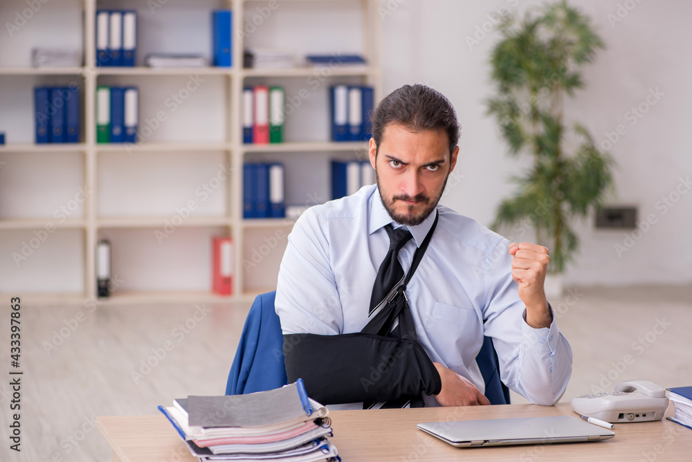 Fototapeta premium Young arm injured male employee working in the office