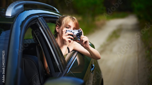 Young beautiful woman in car taking photos while leaning out the window © Nikamata