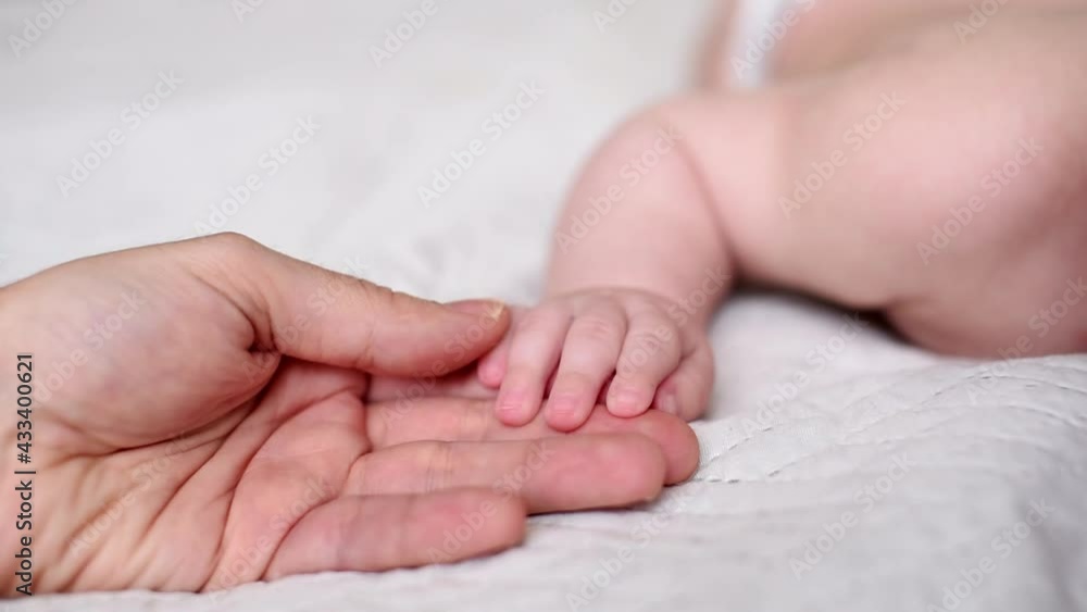 Father gently strokes the little fingers of the newborn's hand. Close up of male's hand and baby's hand. Relaxation, sweet dreams, childhood and family concepts. Dad touching baby hand. Father gently strokes the little fingers of the newborn's hand. Close up of male's hand and baby's hand. Relaxation, sweet dreams, childhood and family concepts. Dad touching baby hand.