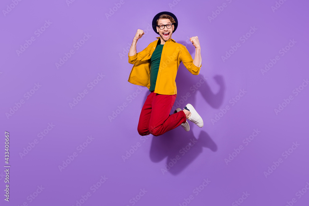 Full length profile side photo of young guy happy positive smile win victory lucky jump isolated over purple color background Full length profile side photo of young guy happy positive smile win victory lucky jump isolated over purple color background