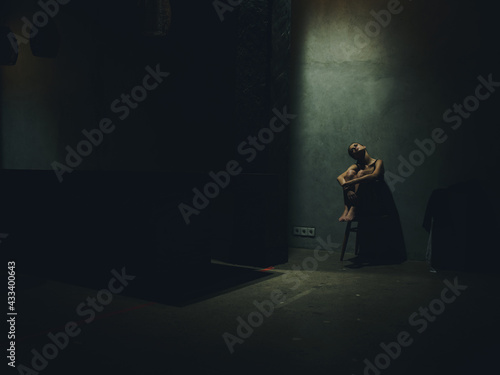lonely woman hugs her knees and sits on a chair in a dark room loneliness depression stress
