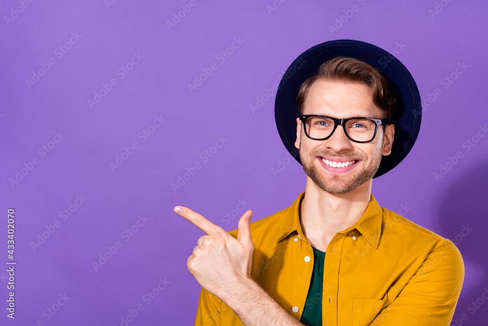 Photo of young man happy positive smile indicate finger empty space advice direct way isolated over purple color background Photo of young man happy positive smile indicate finger empty space advice direct way isolated over purple color background
