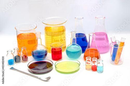 Laboratory glassware with various colored liquids in chemistry laboratory. Volumetric laboratory glassware over white background