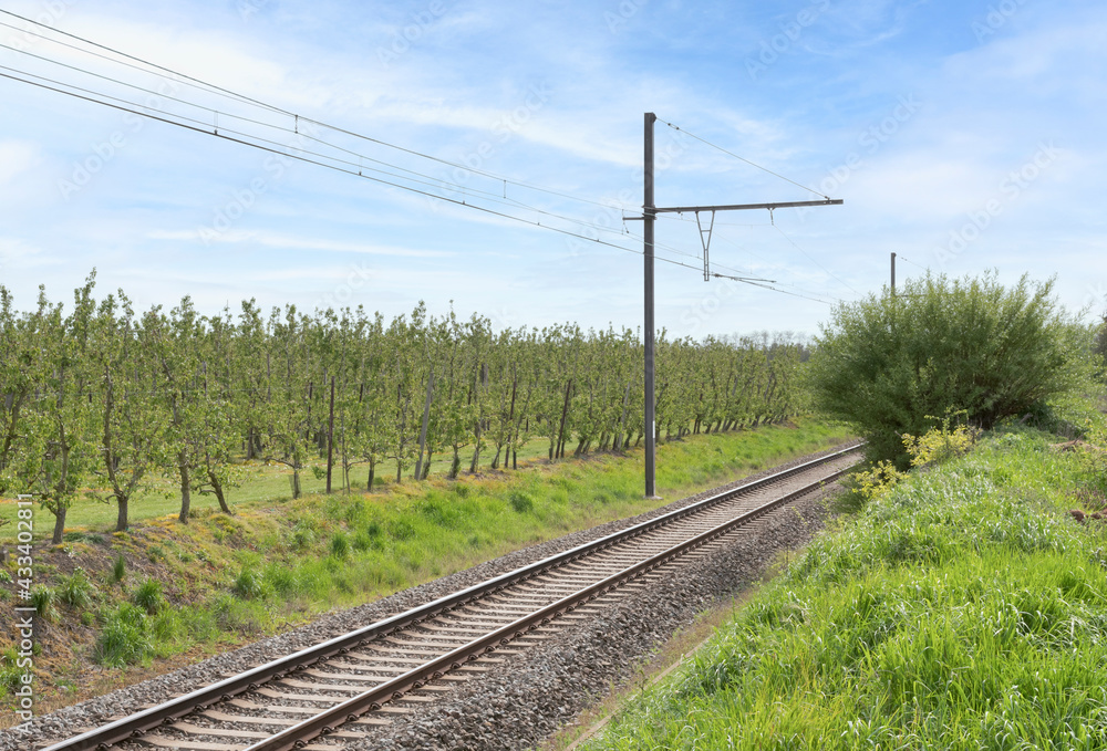 Railway section passing through the countryside near apple orchard Railway section passing through the countryside near apple orchard