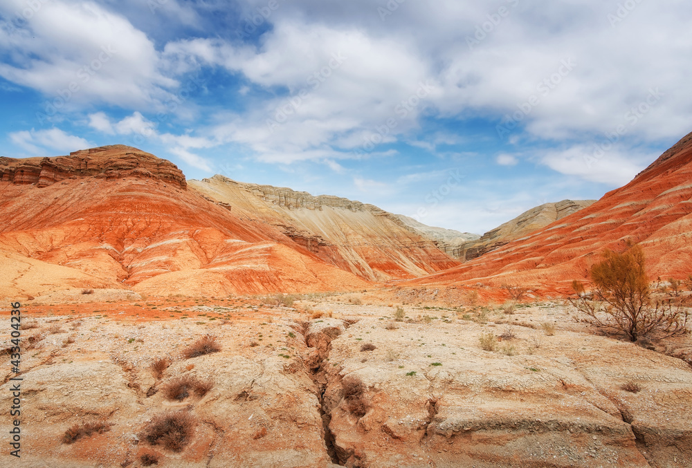 Hills of ancient multi-colored sediments, red yellow and white clay, erosion, desert vegetation. View of the Altyn-Emel park in Kazakhstan