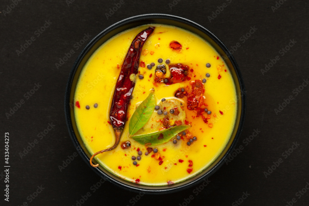 Close-up of Indian traditional kadhi or kadi pakora yogurt and gram flour and turmeric served hot in a black bowl. Over black background.
Close-up of Indian traditional kadhi or kadi pakora yogurt and gram flour and turmeric served hot in a black bowl. Over black background.