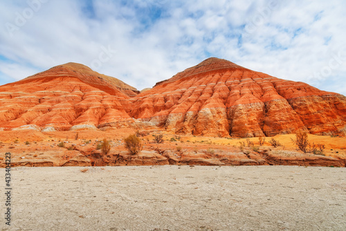 Hills of ancient multi-colored sediments, red yellow and white clay, erosion, desert vegetation. View of the Altyn-Emel park in Kazakhstan