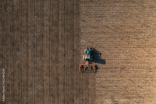 Obraz na plátně Top view of a tractor harrowing soil on an agriculture field