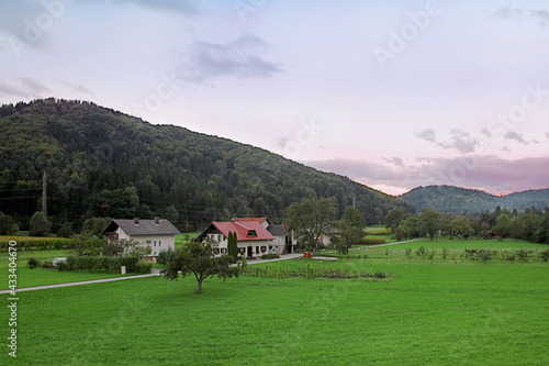 Idyllic mountain village landscape with little houses with red roof, vast green lawns. Evening sunset time, beautiful nature. Outdoors, copy space.