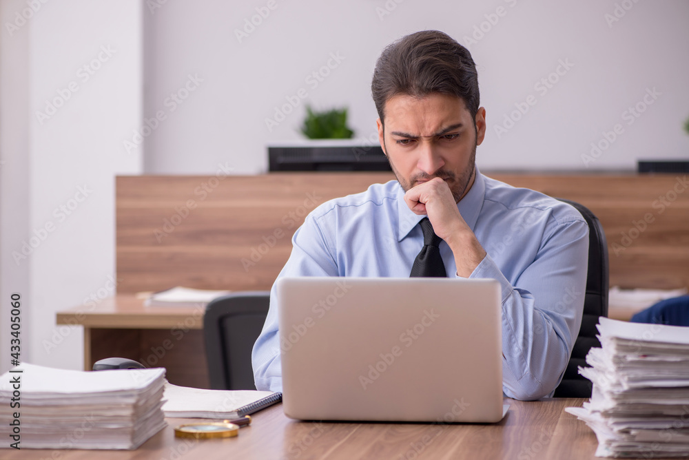 Young male employee and too much work in the office Young male employee and too much work in the office