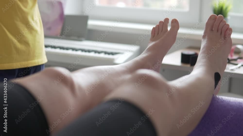 A woman is developing a foot with a post-surgery instructor at home. Close-up of the legs on the roller A woman is developing a foot with a post-surgery instructor at home. Close-up of the legs on the roller