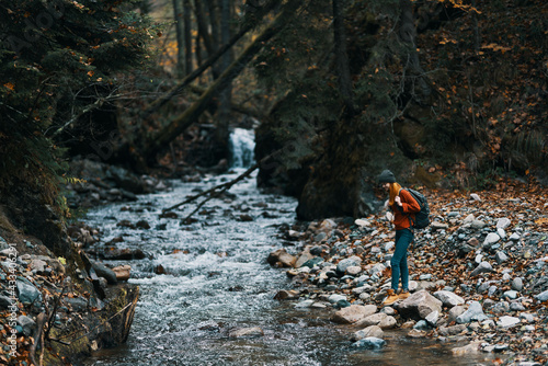 woman in a sweater hat near the river and trees in the background