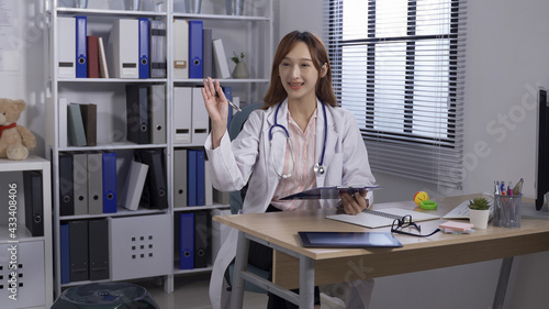 in medical clinic, pediatrician raising hand and inviting her patients to be seated with a warm smile. authentic lifestyle