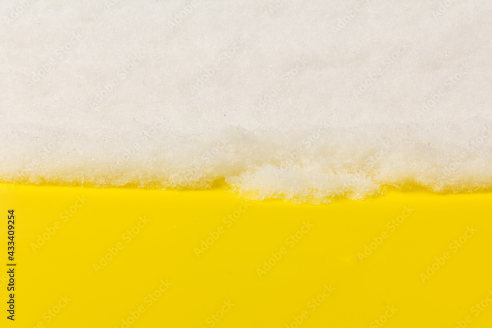 Heap of white snow on yellow background.The structure of snow and ice. Close-up. Heap of white snow on yellow background.The structure of snow and ice. Close-up.