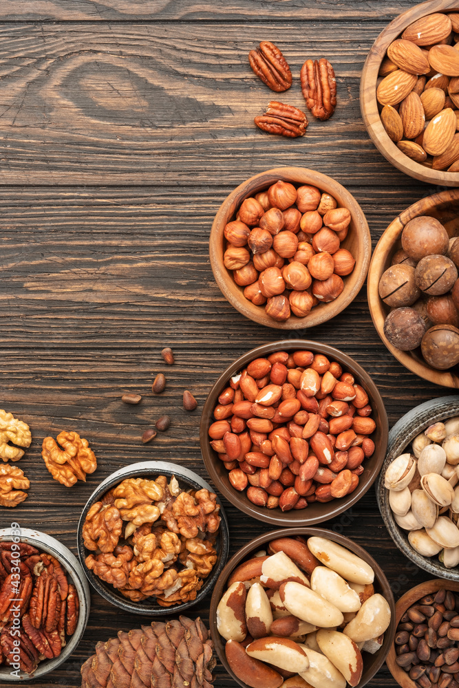 Nuts in bowls. Walnuts, pistachios, pecans, macadamia, almonds and other. Healthy food snacks mix on wooden background, top view Nuts in bowls. Walnuts, pistachios, pecans, macadamia, almonds and other. Healthy food snacks mix on wooden background, top view