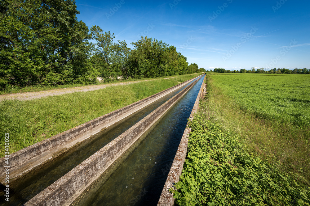 Fototapeta premium Two small concrete irrigation canals in the countryside, Padan Plain or Po valley (Pianura Padana, Italian). Mantua province, Italy, southern Europe.