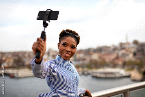 Beautiful african woman taking a selfie in modern city. Cute young woman taking a selfie on a bridge