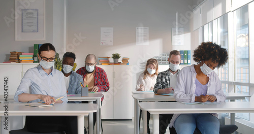 Multiethnic people in room in protective face mask attending lesson in extension school