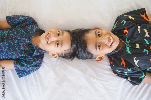 Cute asian children brothers lying on sofa or bed and having fun together. Indonesian siblings spending timeat home photo