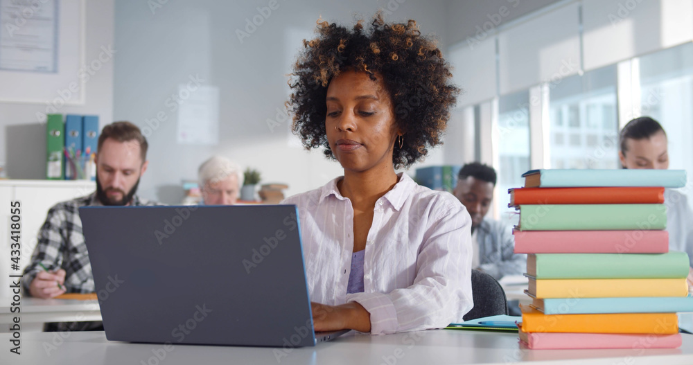 Multiethnic students sitting in classroom using laptop Multiethnic students sitting in classroom using laptop