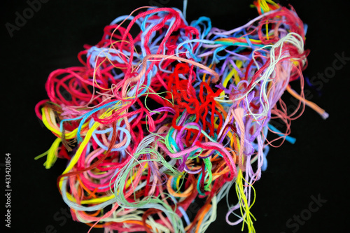 Ball of multicolored tangled threads for needlework on black background