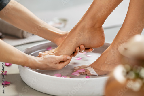 Beautician washing woman feet for pedicure treatment photo