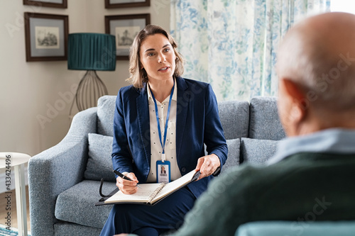 Social worker talking with senior man during home visit