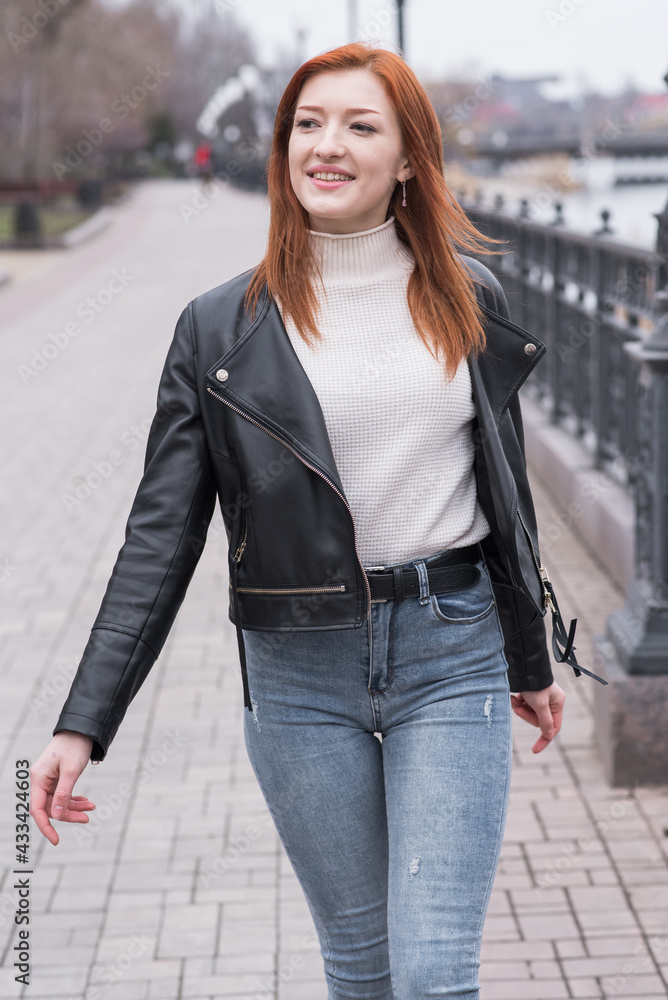 Fototapeta premium Portrait of a beautiful and positive redhead woman with clothes in grunge style. Posing while walking