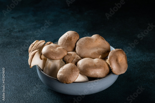 Eringi mushrooms on plate on a dark background. Pleurotus eringi. Vegan food concept. King Oyster Mushroom in a bowl.