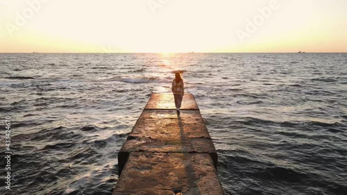 Slow motion shot of young woman walking on stone pier
