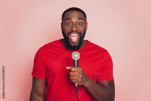 Dark skin guy sing karaoke microphone isolated over pink background
