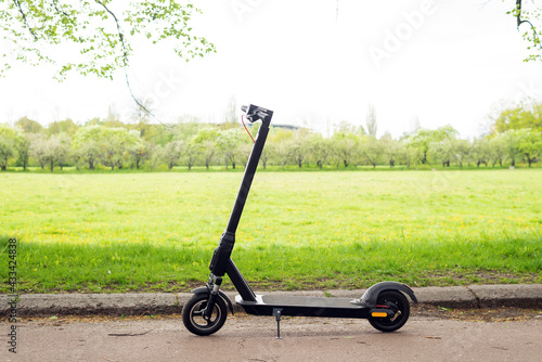 Electric scooter in the park. On the green meadow background. Modern eco-transport. Concern for the environment.