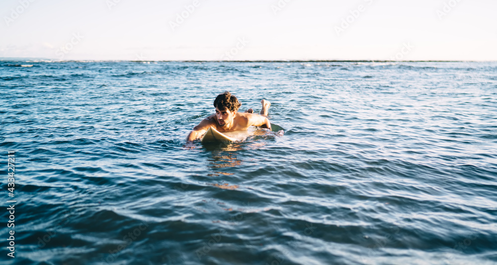Strong surfer on surfboard floating on seawater