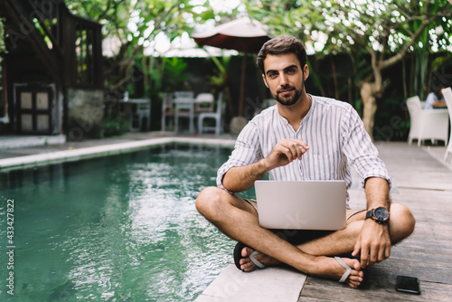 Young man with working on laptop while enjoying summer holiday #433427822