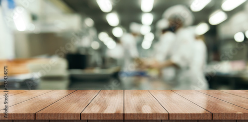 Wood table top on blur kitchen room background.