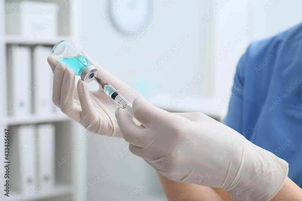 Doctor filling syringe with medication from vial in hospital, closeup Doctor filling syringe with medication from vial in hospital, closeup