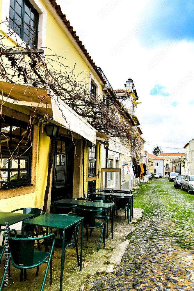 Naklejka premium Empty bar terrace on Narrow street of Lisbon in a cloudy day
